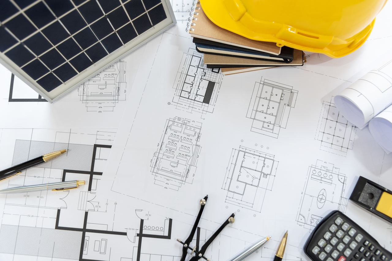 Flat lay of solar home plans with materials around it