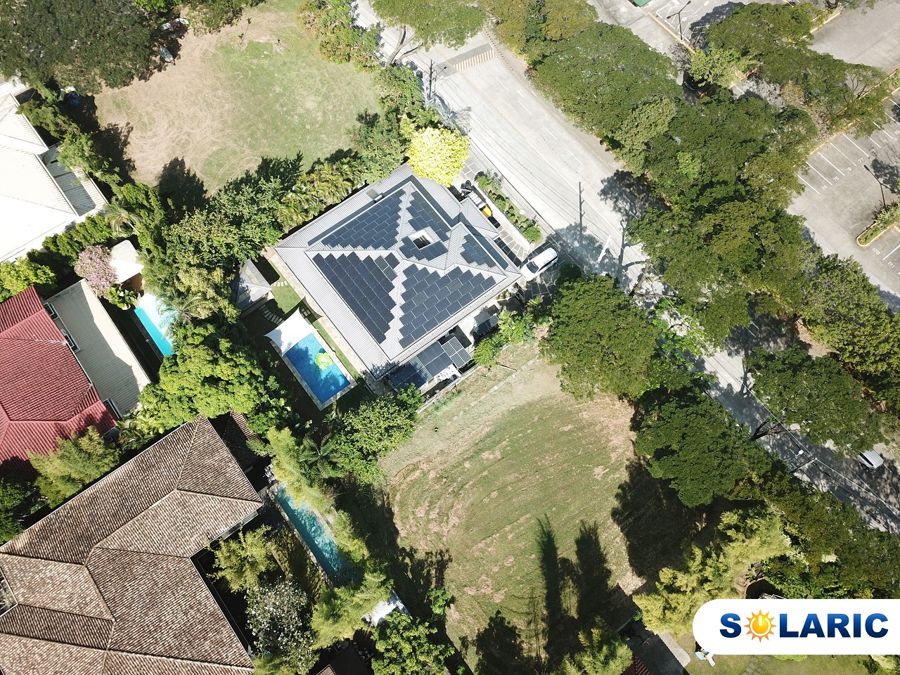 Drone shot of a village with a house's roof full of solar panels as the centerpiece