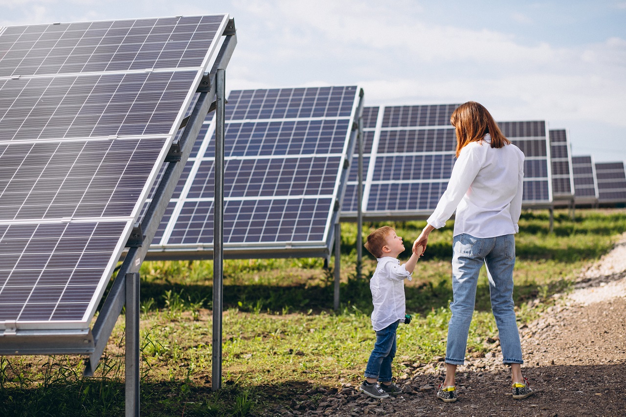 Mom and young son standing beside solar panels