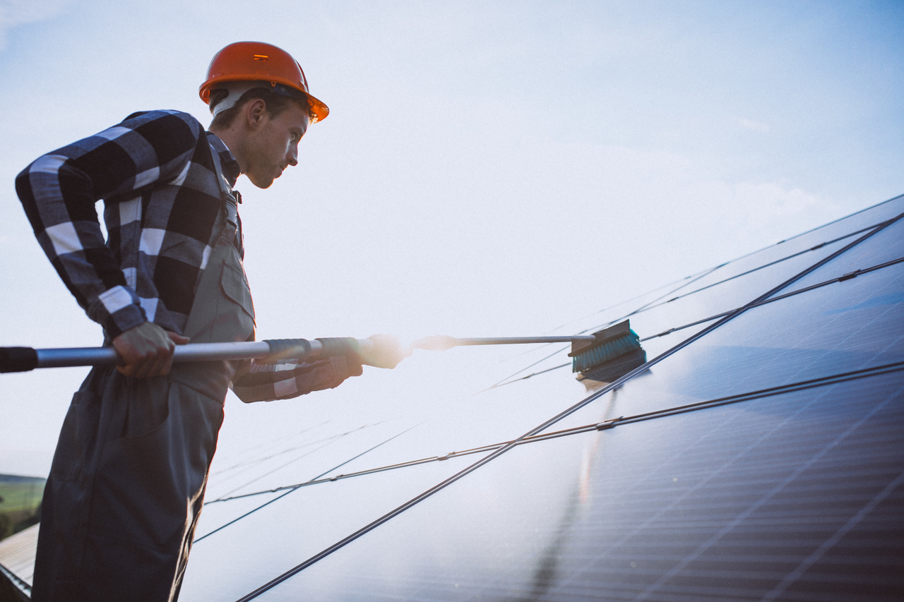 A worker cleaning a solar panel