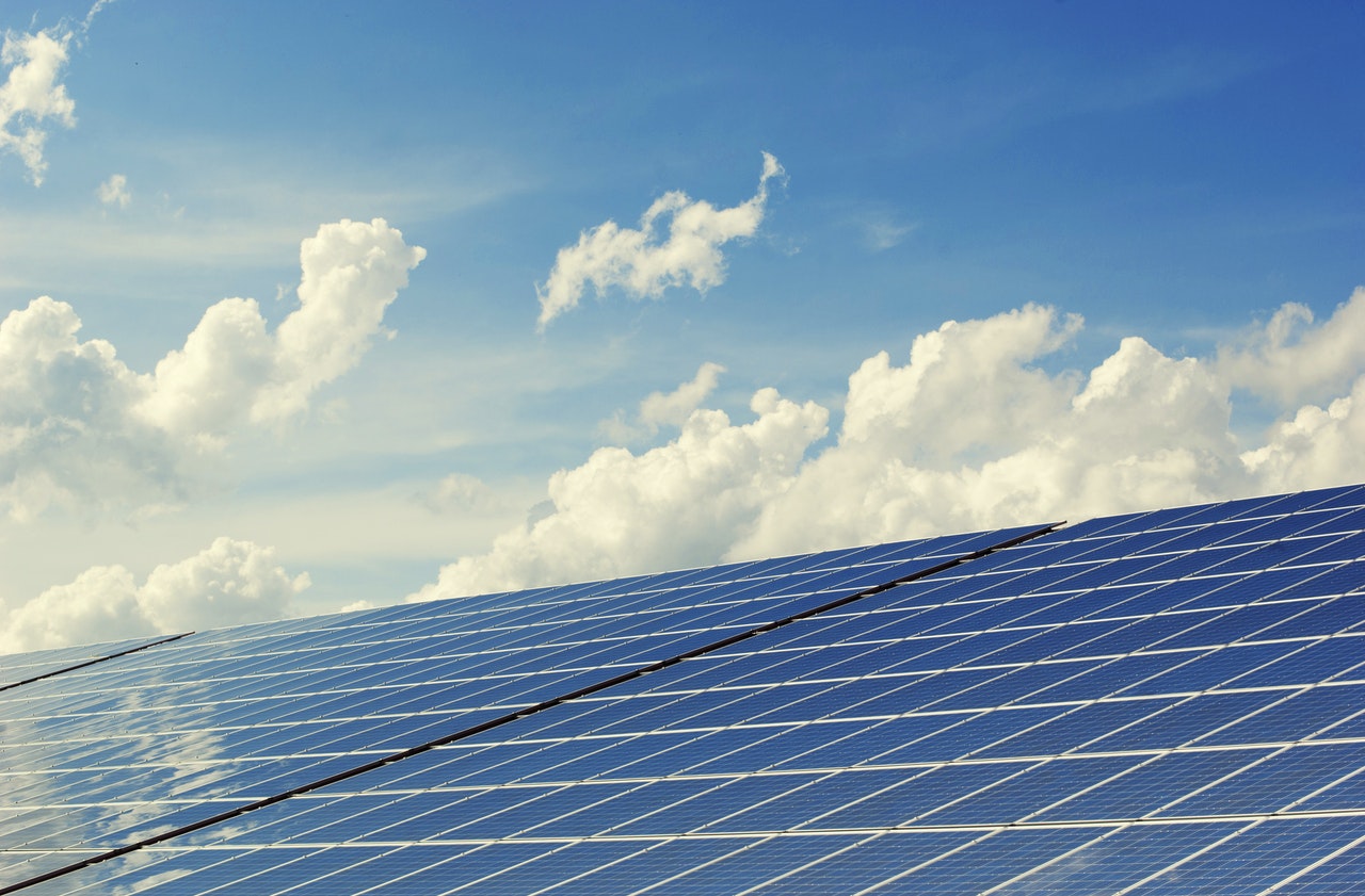 close-up shot of solar panels with the blue sky and white clouds above shown