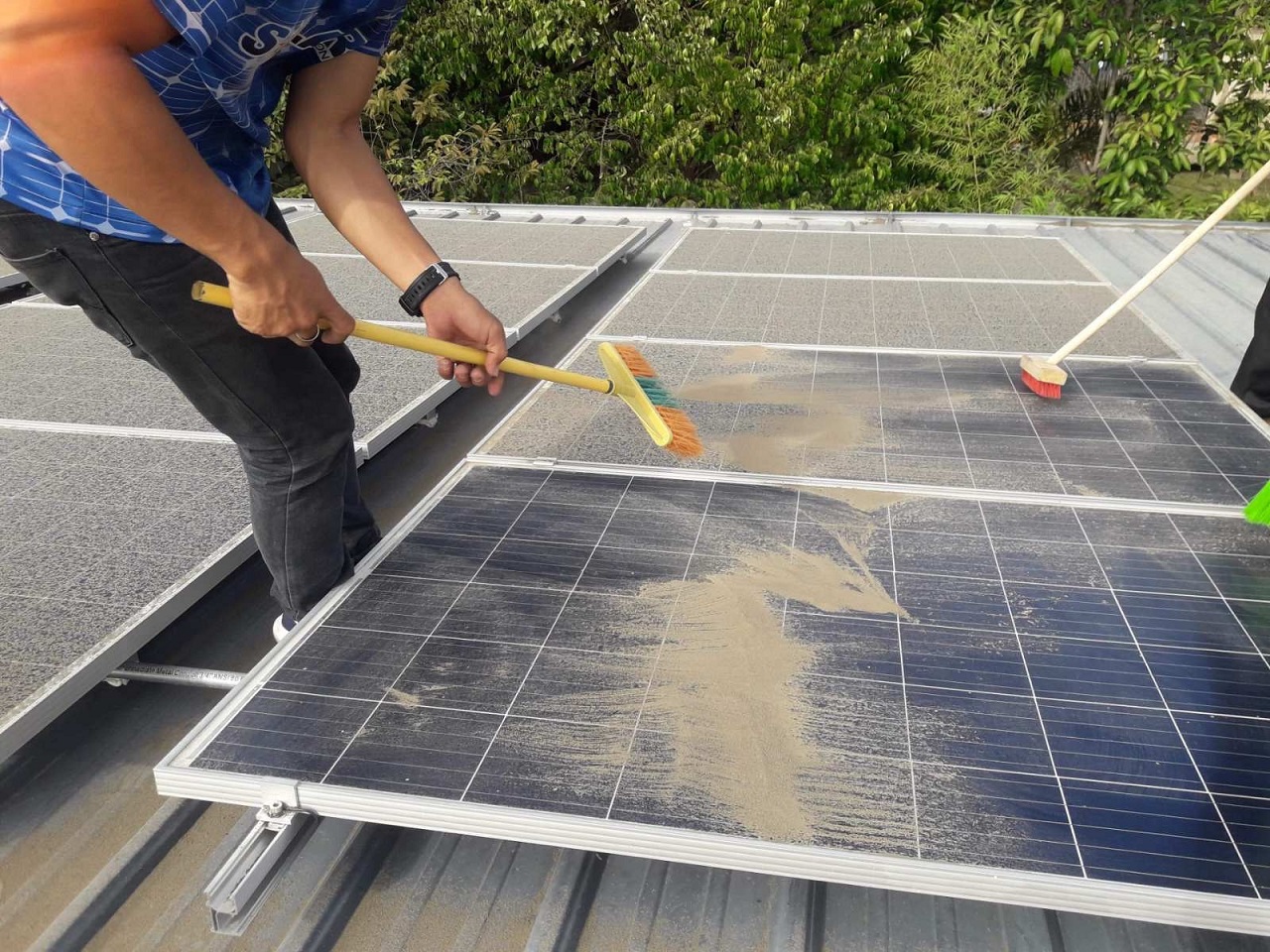 A professional brushing dust off of a solar panel