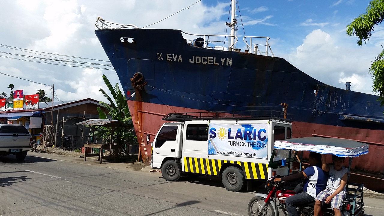 A Solaric van parked in front of a ship that has grounded on to land