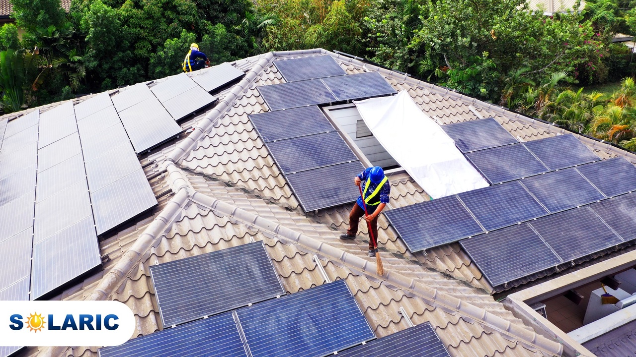 Two Solaric employees cleaning solar panels on a rooftop